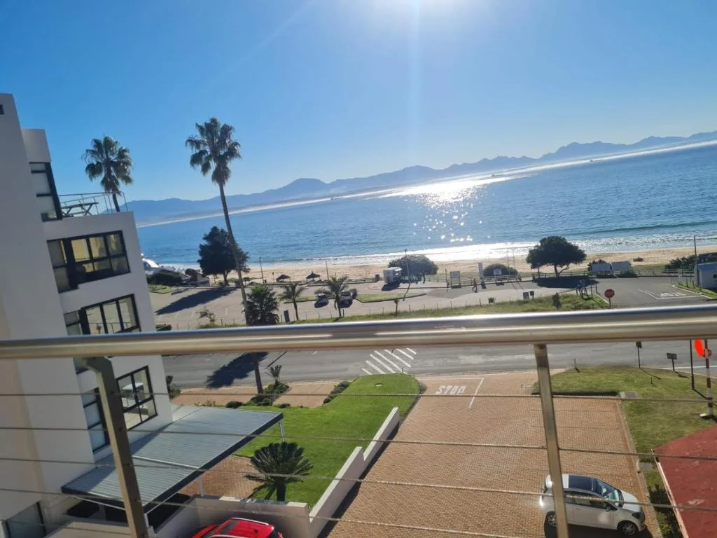 Scenic beachfront view with mountains and sparkling ocean from balcony