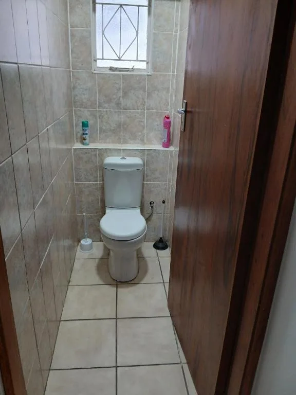 Compact bathroom with toilet, tiled walls, and small window