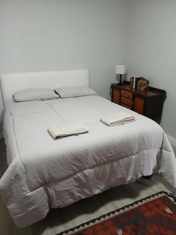 Bright bedroom with white queen bed, wooden nightstand, and fresh linens
