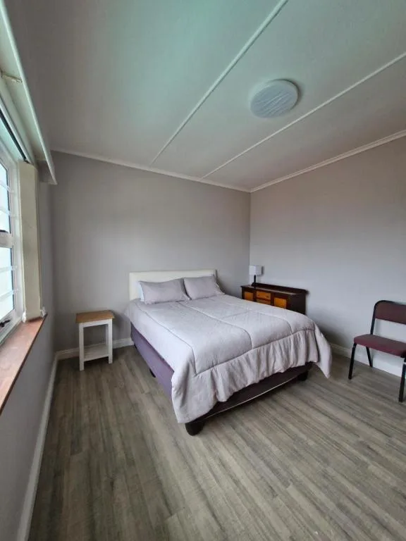 Bright bedroom with queen bed, bedside table, and window light