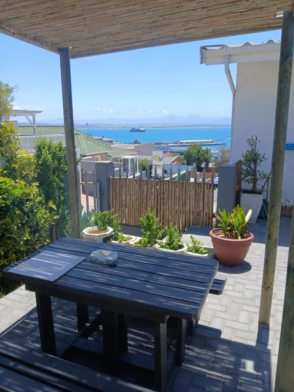 Covered deck with dining table overlooking coastal bay views and mountains
