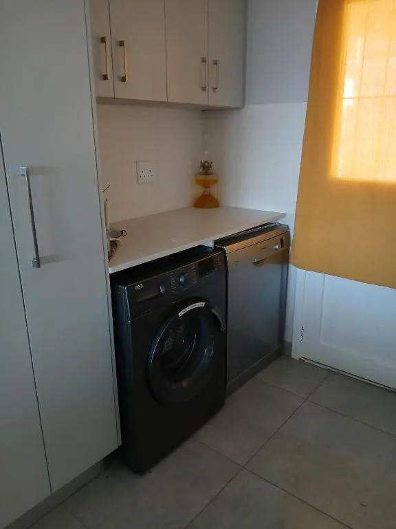 Compact laundry room with black washing machine and white cabinetry