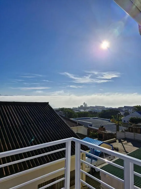 Scenic coastal town view with rooftops and distant hills under clear blue sky