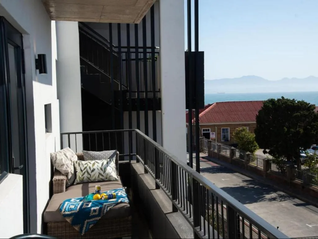 Coastal balcony with seating, ocean view, and neighboring buildings