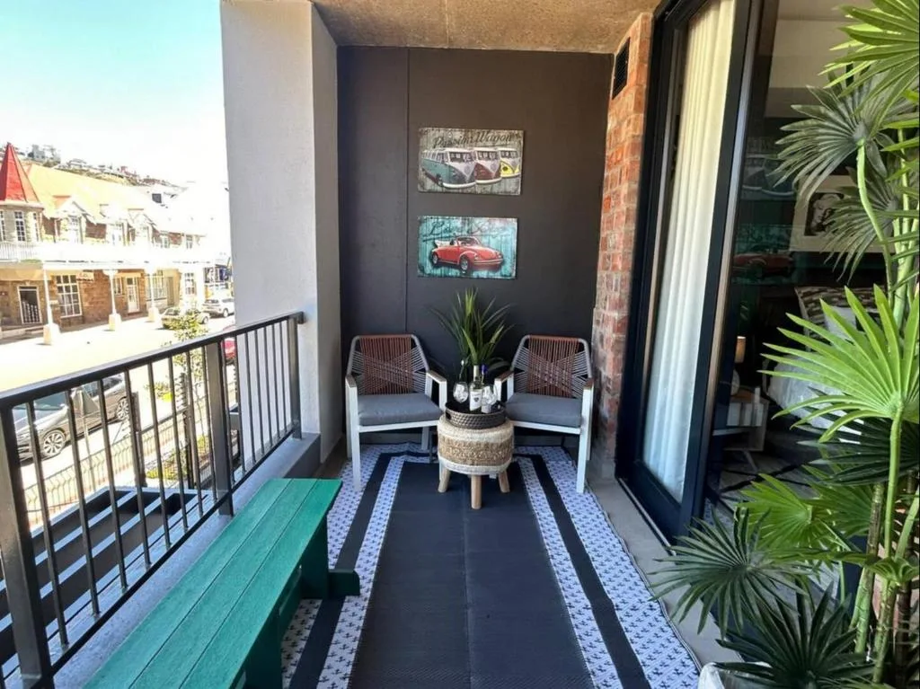 Stylish balcony with seating, potted plants, and town views