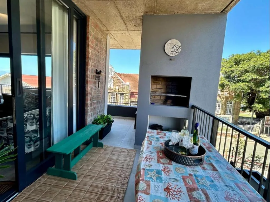Outdoor deck with dining table, bench seating, and built-in braai fireplace