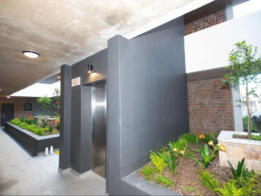 Modern black entrance pavilion with steel door and planted gardens
