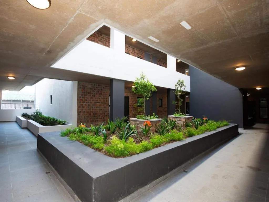 Modern apartment building entrance with planted garden beds and contemporary architectural design