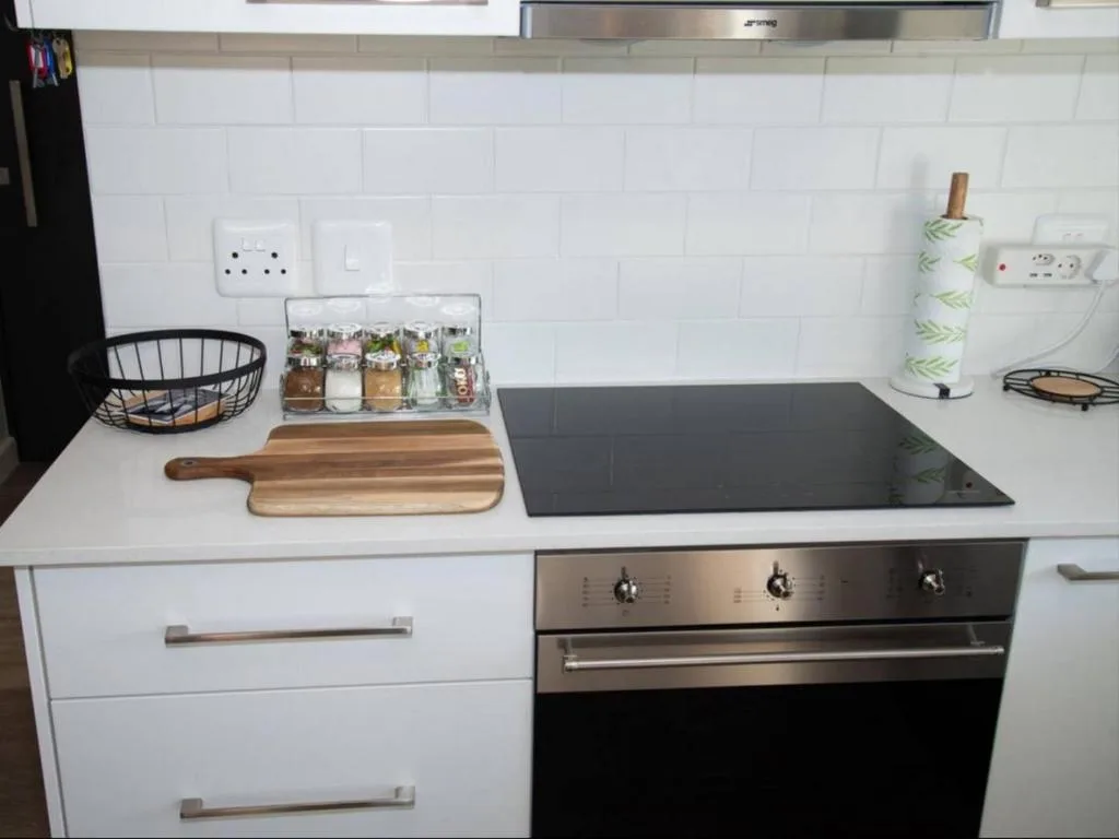 Modern kitchen with white cabinetry, black cooktop, and organized countertop items