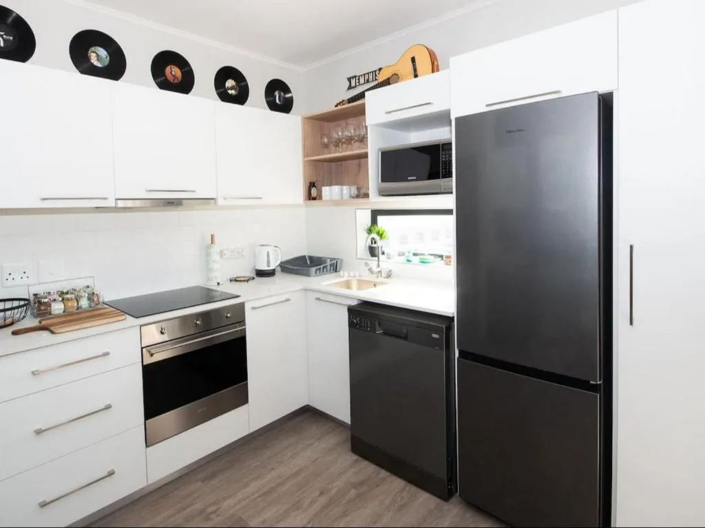 Modern kitchen with white cabinetry, stainless steel appliances, and vinyl record decor