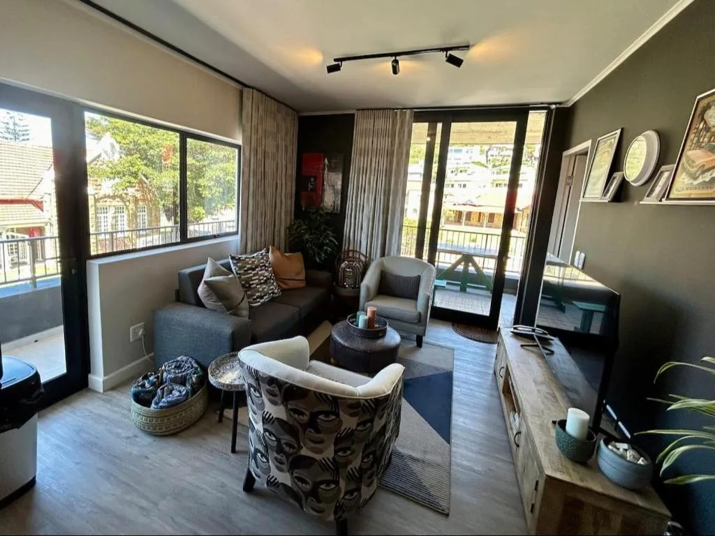 Modern lounge with sofa, armchairs, and town views through large windows