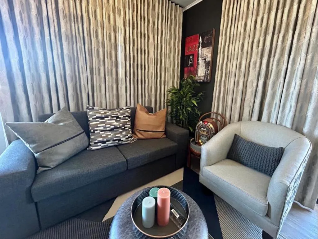 Modern lounge with dark sofa, cream armchair, and stylish decor