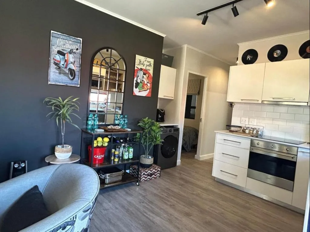 Modern lounge with grey accent wall, vintage decor, and open-plan kitchen view