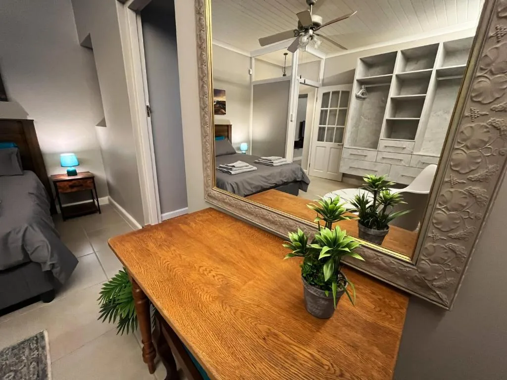 Spacious bedroom with wooden desk, large mirror, built-in wardrobes, ceiling fan