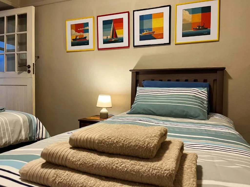 Cozy bedroom with striped bedding, nautical artwork, and folded towels