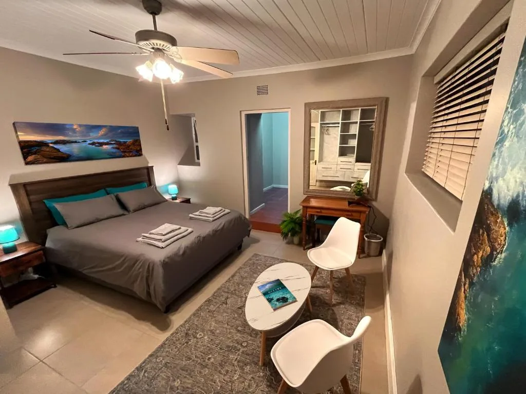 Modern bedroom with queen bed, ceiling fan, and coastal artwork on walls