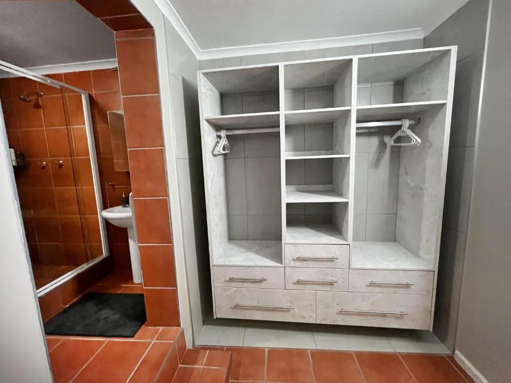 Spacious bedroom with large built-in white wardrobe and storage compartments