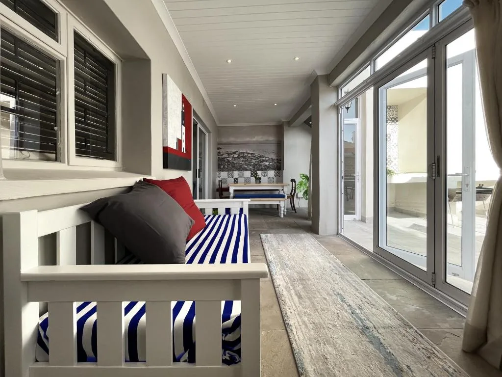 Covered deck with seating, striped rug, and sliding glass doors to interior