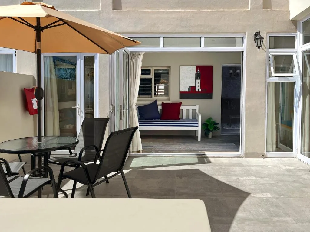 Covered patio with umbrella overlooking open-plan bedroom and lounge area