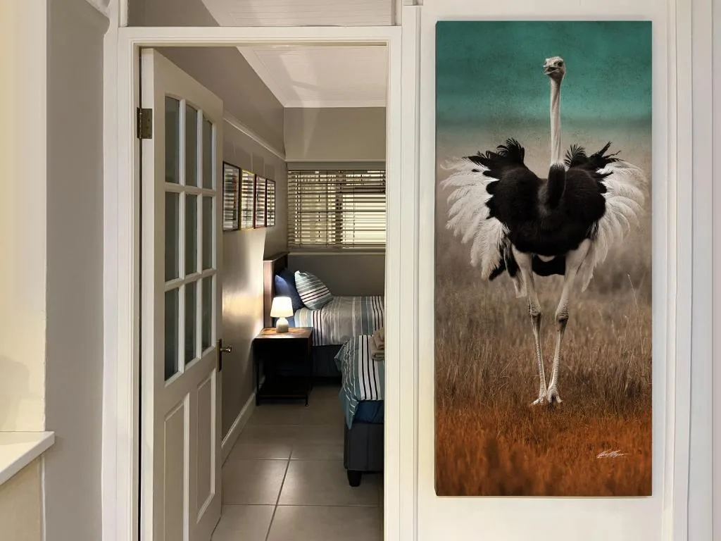 Hallway with open bedroom door and ostrich artwork on wall