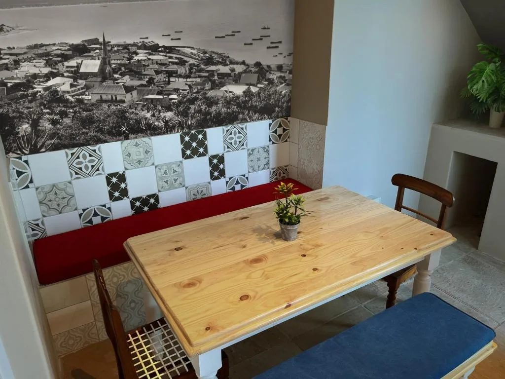 Wooden dining table with decorative tilework and coastal town artwork