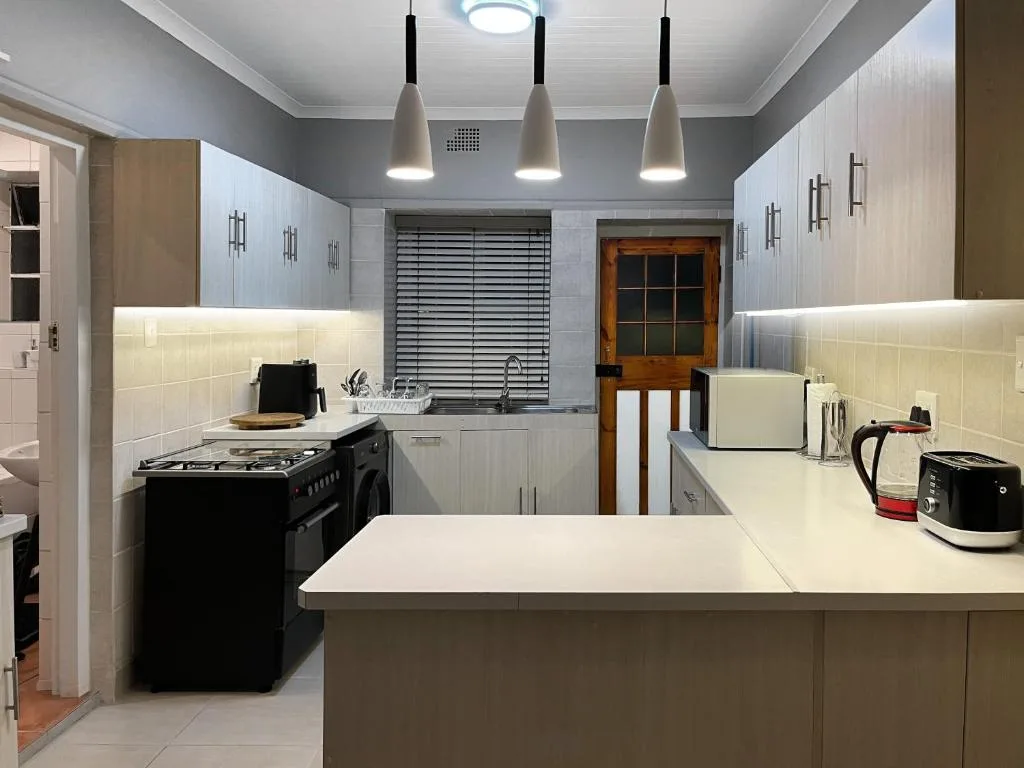 Modern kitchen with island counter, black stove, white cabinetry, pendant lights