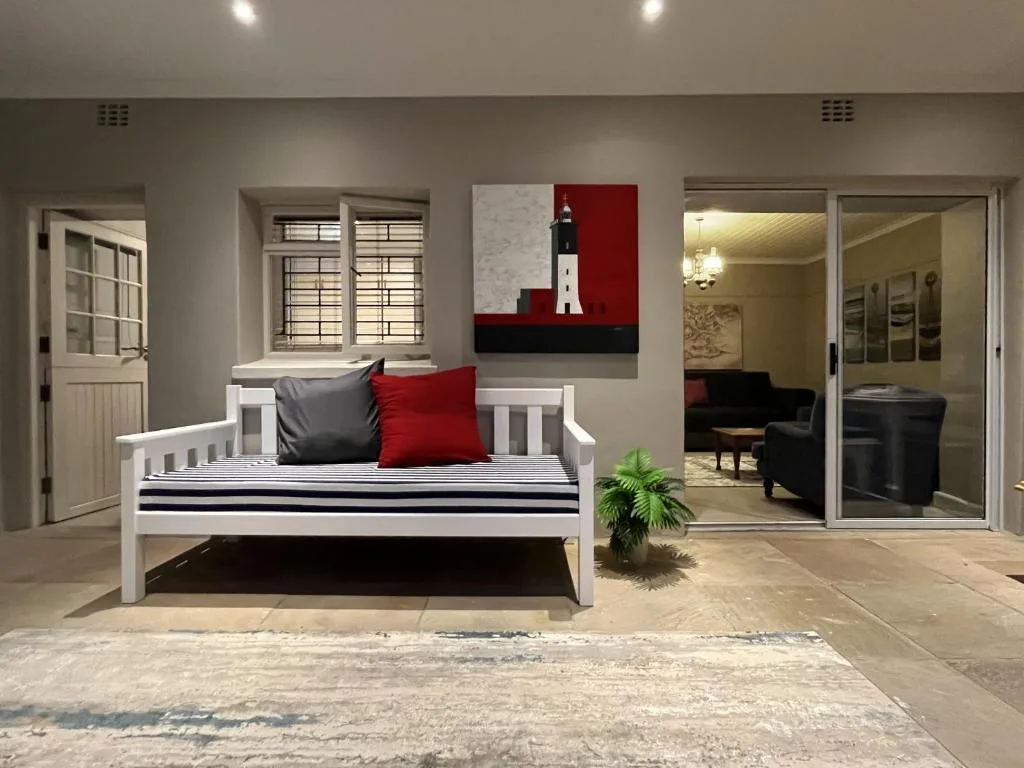 Modern lounge with white daybed, red and black cushions, lighthouse artwork