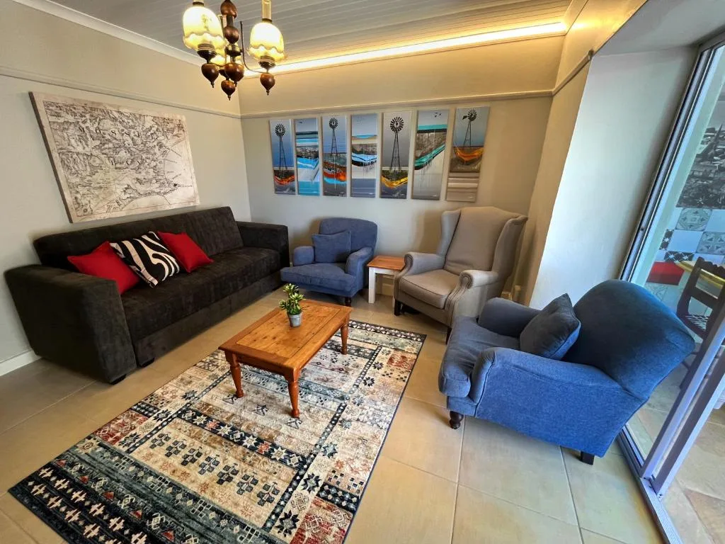 Modern living room with black sofa, blue armchairs, wooden coffee table, and wall art