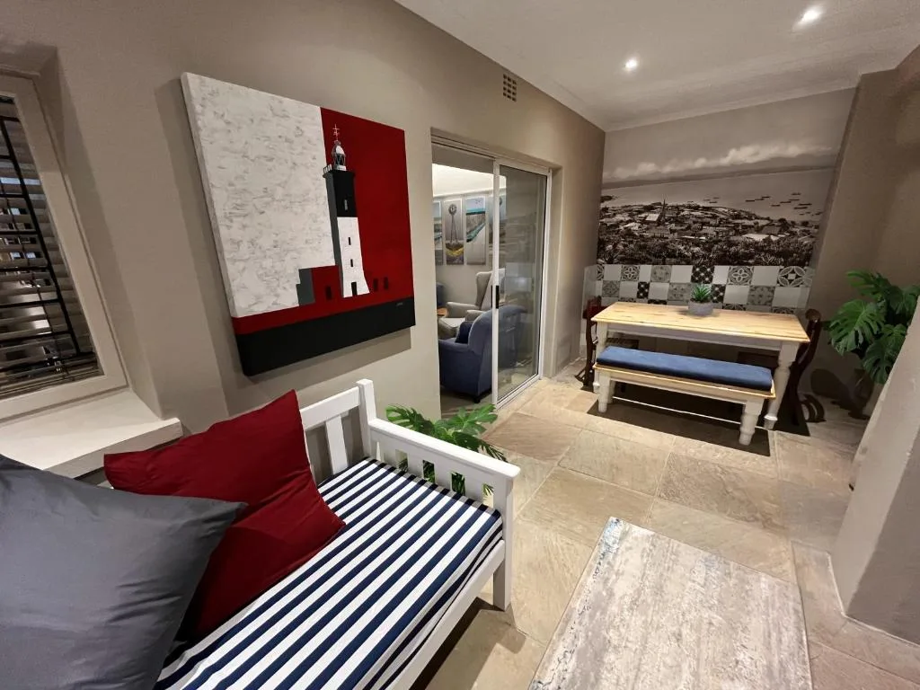 Modern lounge with red and navy accents, sofa, and coastal artwork