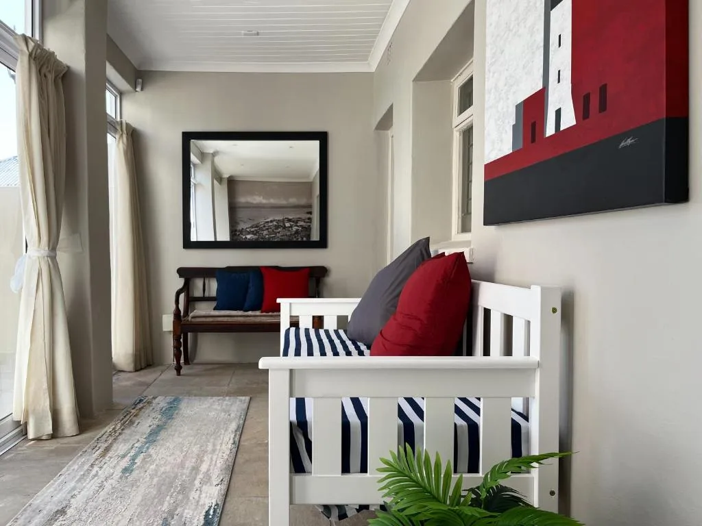 Modern lounge with white bench seating, red and navy cushions, contemporary wall art
