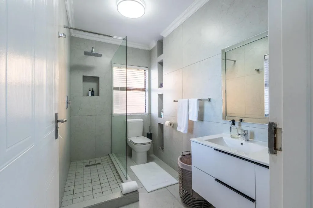 Modern bathroom with walk-in shower, white vanity, and large mirror