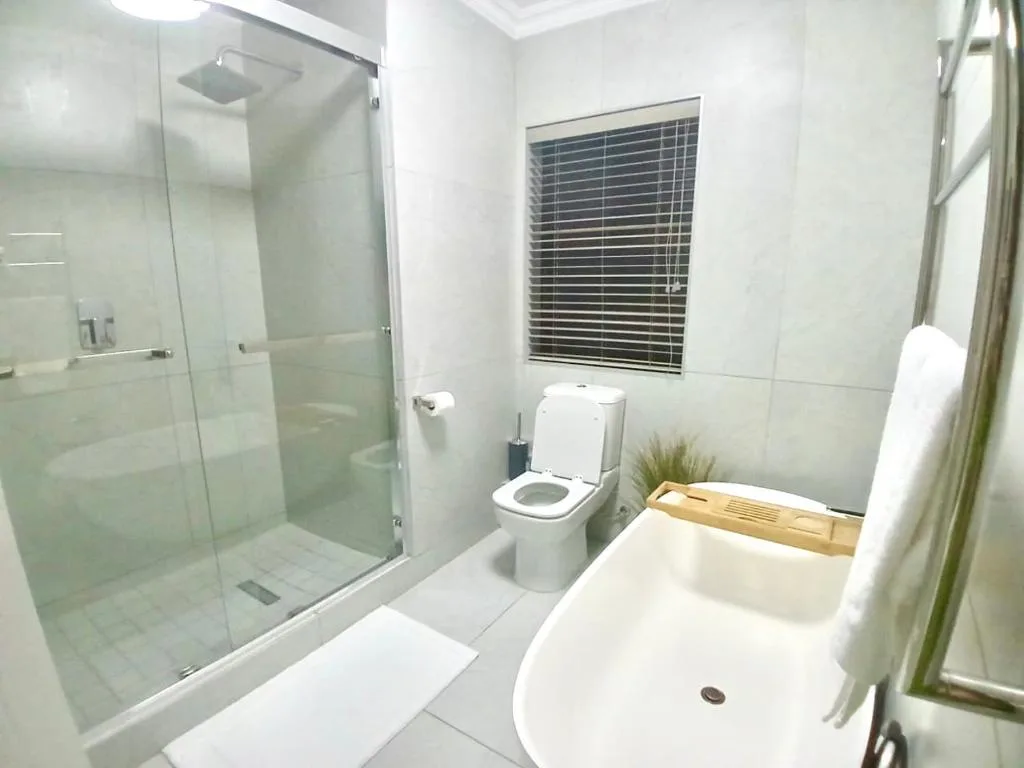 Modern bathroom with walk-in shower, toilet, and white freestanding bathtub