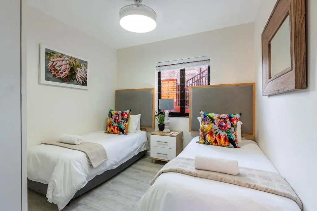 Bright twin bedroom with colorful cushions and modern amenities throughout