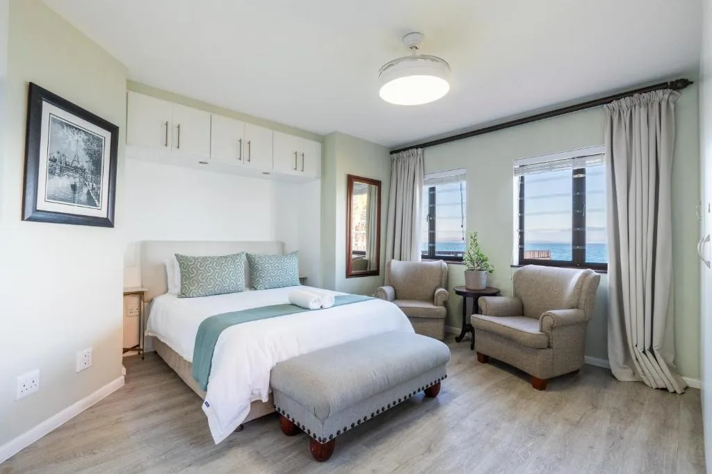 Spacious bedroom with ocean view, comfortable bed, and seating area