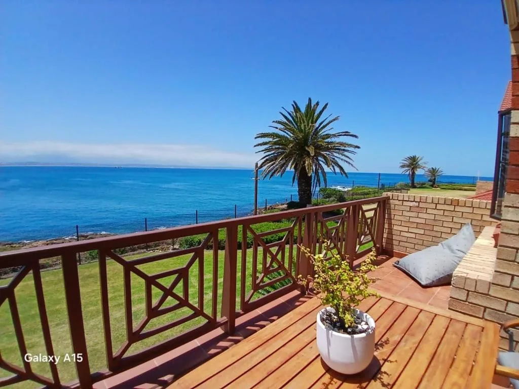 Wooden deck with ocean view, palm trees, and coastal landscape