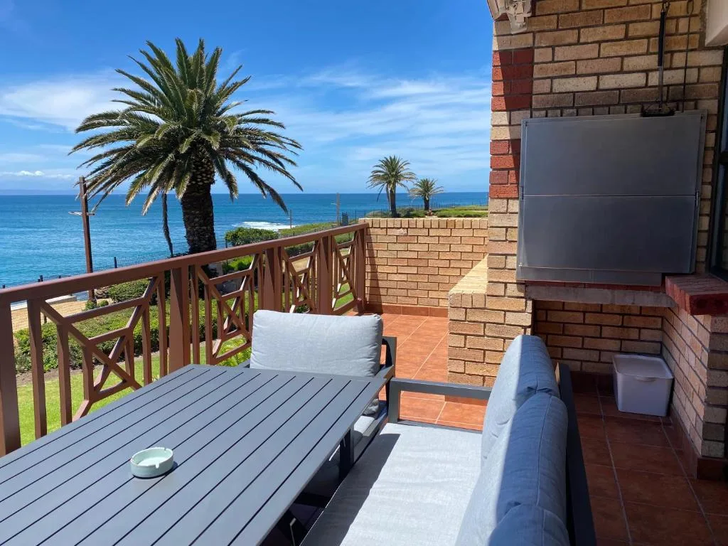Oceanfront deck with seating, palm trees, and coastal views