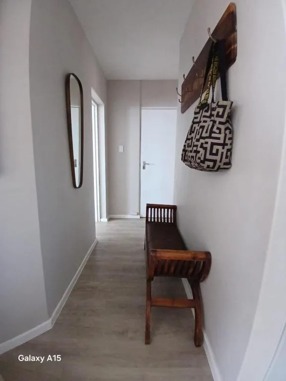 Narrow hallway with mirror, wooden chair, and decorative wall hooks