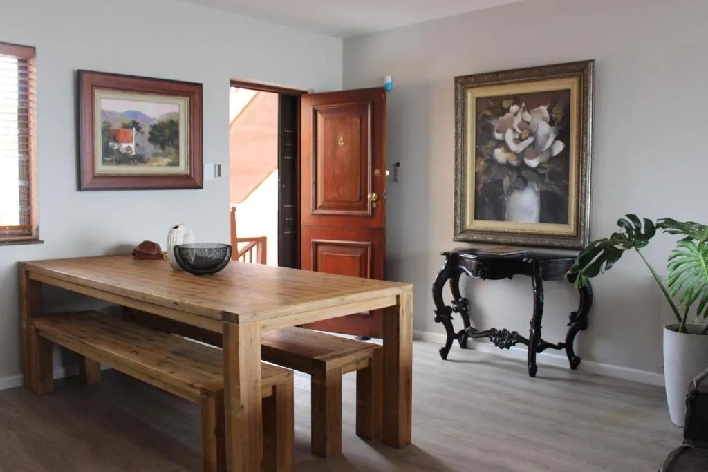Wooden dining table with bench seating in bright, art-filled room