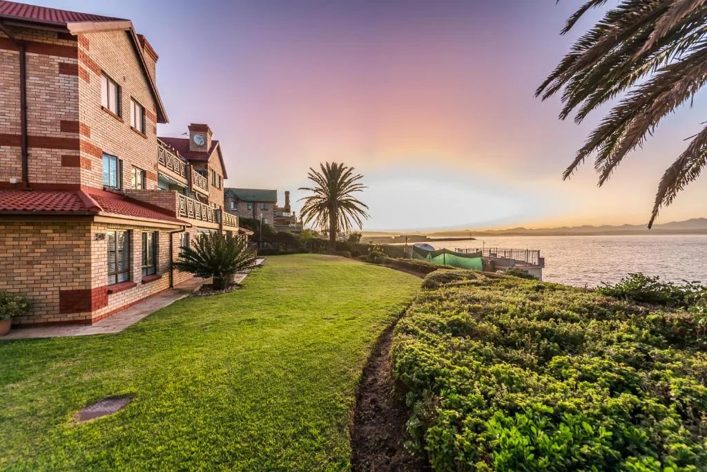 Brick building with manicured lawn overlooking lagoon at sunset