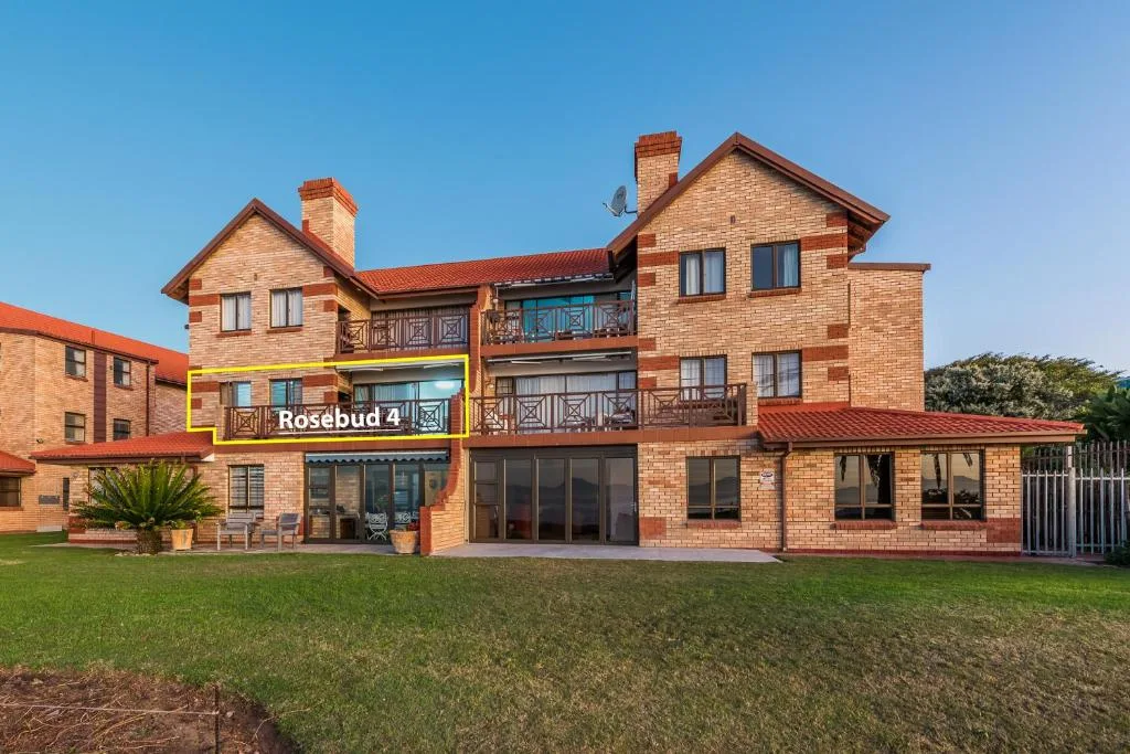 Brick residential building with multiple levels and balconies, green lawn foreground