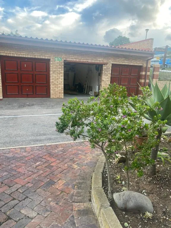 Brick facade with red garage doors and manicured garden entrance
