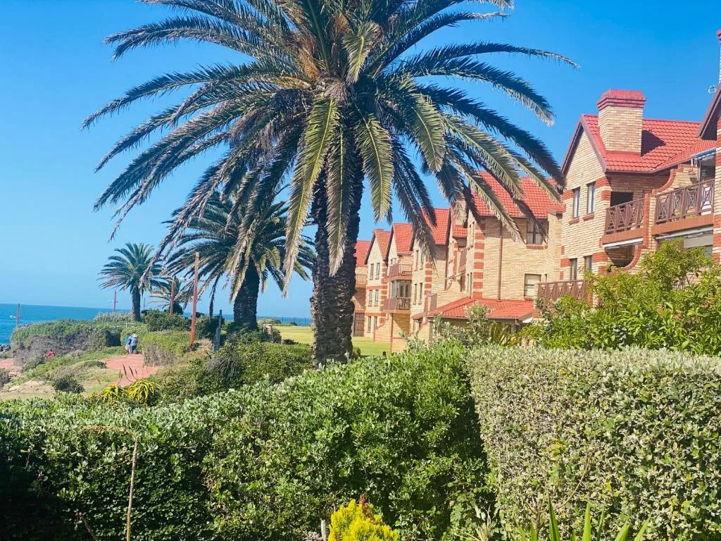 Victorian brick building with red roof and palm trees, ocean views