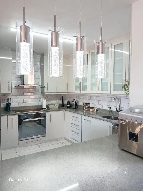 Modern kitchen with white cabinetry, stainless steel appliances, and pendant lights