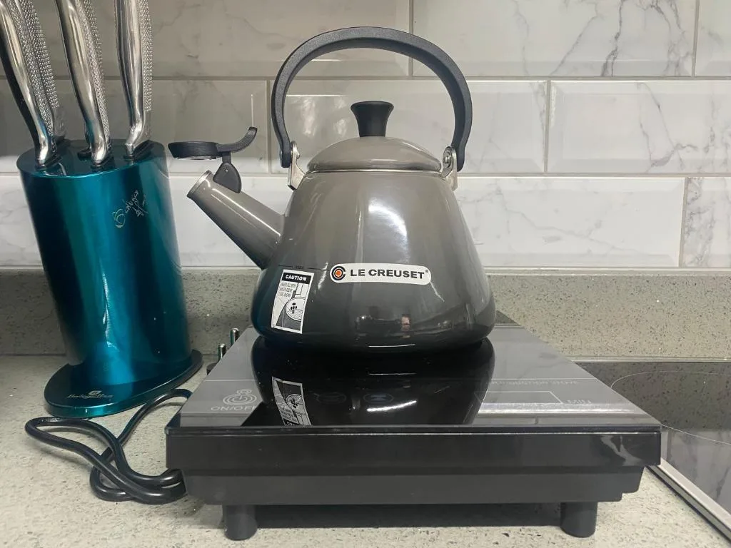 Black Le Creuset kettle on portable hob with knife block nearby