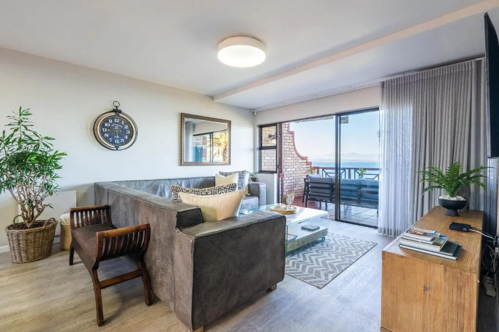 Spacious living room with sofa, armchair, and ocean view through sliding doors