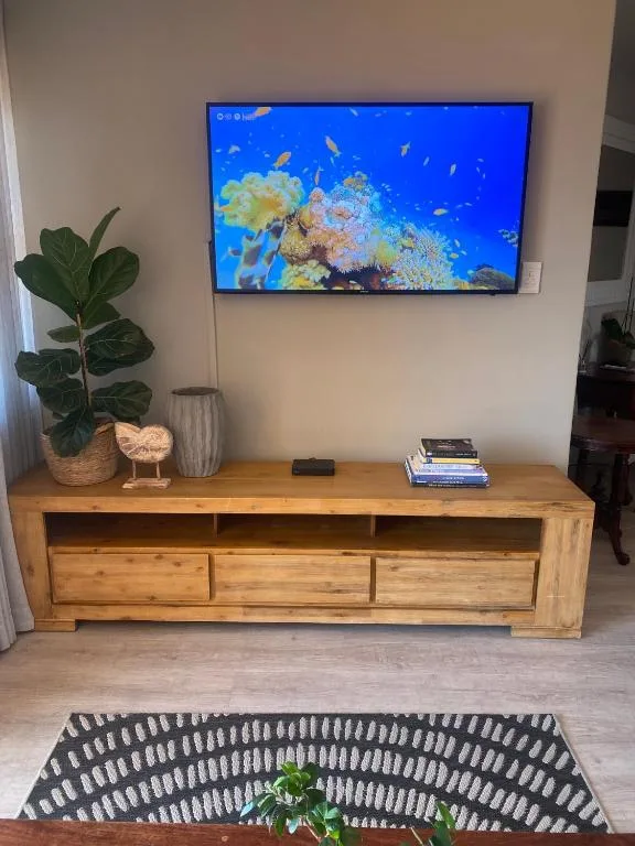 Living room with wooden TV stand, wall-mounted television displaying coral reef scene