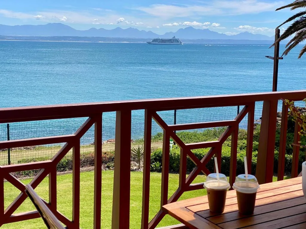 Ocean view from deck with mountains, cruise ship, and refreshments