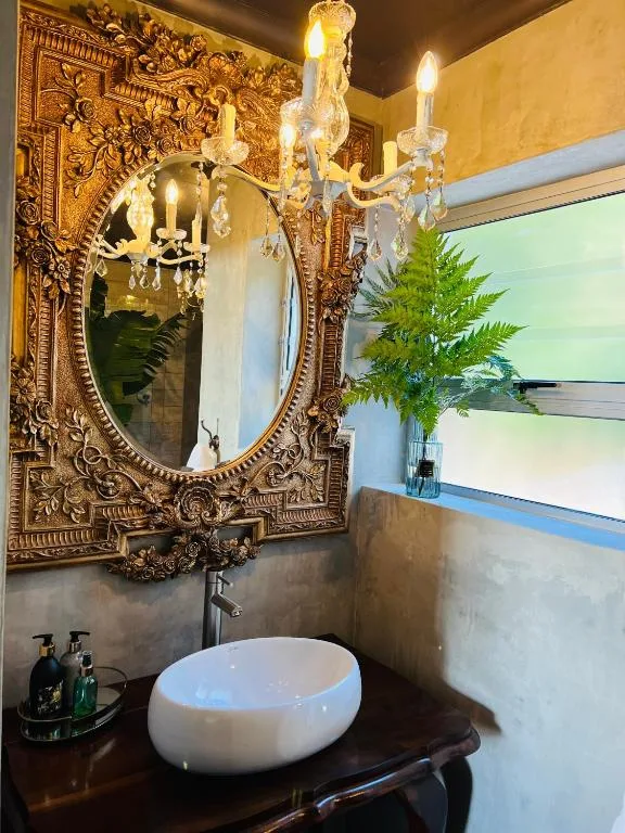 Ornate bathroom with decorative gold mirror, crystal chandelier, and round vessel sink