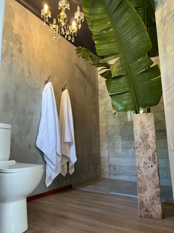 Modern bathroom with chandelier, towel rails, and tropical plant decor