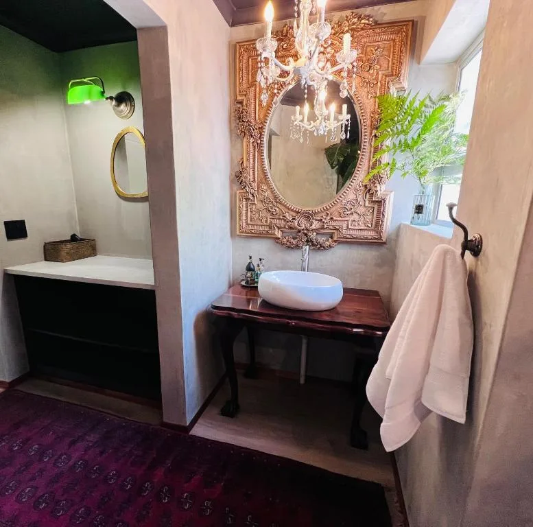 Elegant bathroom with ornate mirror, chandelier, and vessel sink on dark wood vanity